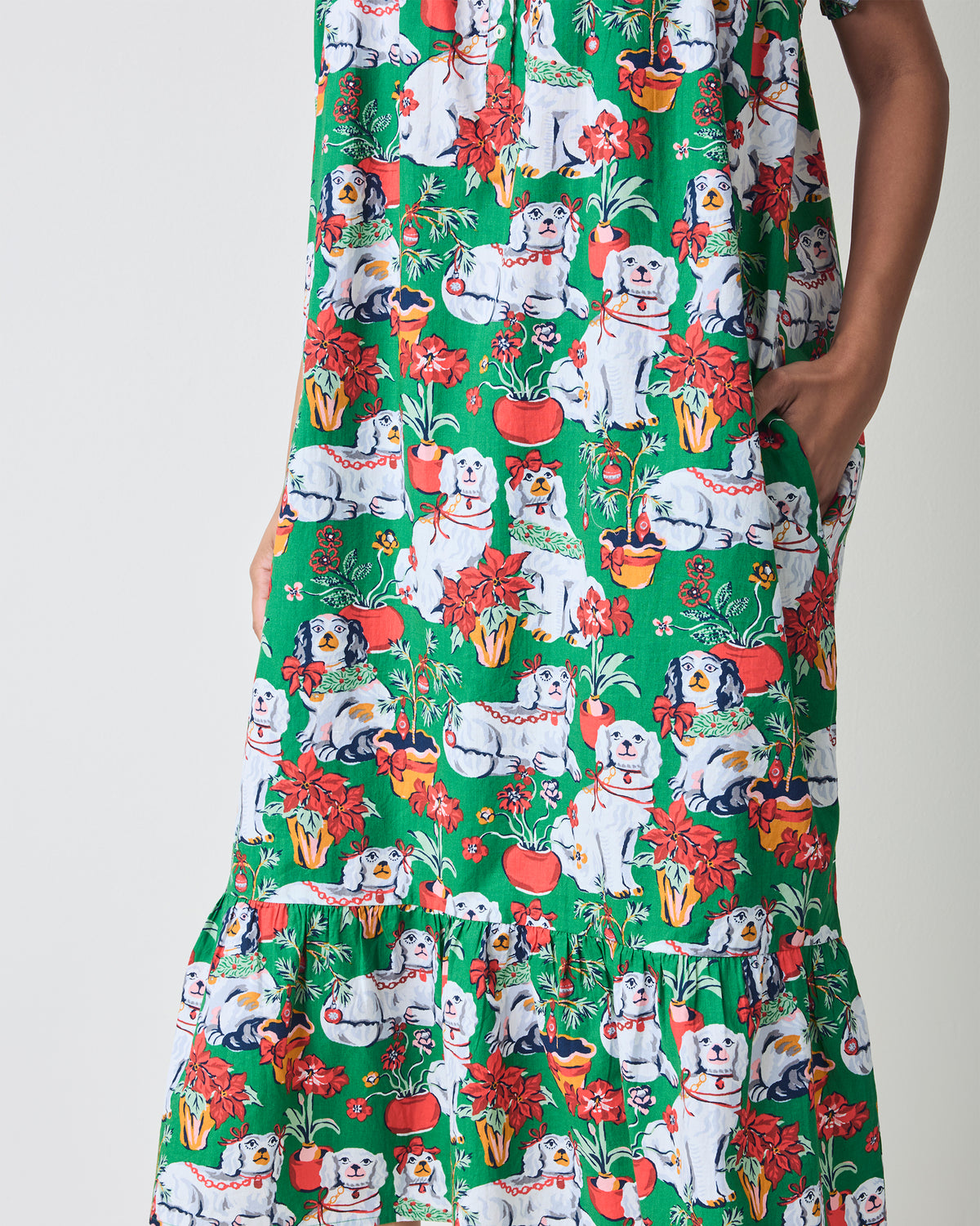 Close detail of the green Good Dog Christmas nightgown showing its dog-and-poinsettia print, side pocket, and ruffled lower edge.