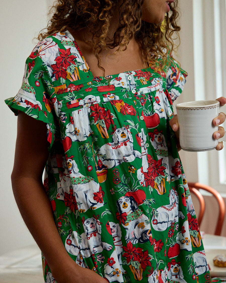 Close view of the green Good Dog Christmas nightgown showing its square neckline, button front, ruffled trim, and dog-and-poinsettia print.
