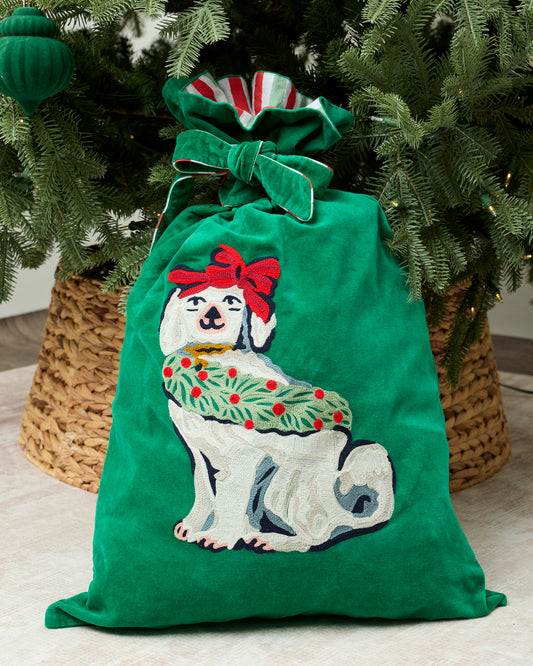 Green Good Dog Christmas gift sack with a bow-wearing white dog design, displayed beneath a Christmas tree