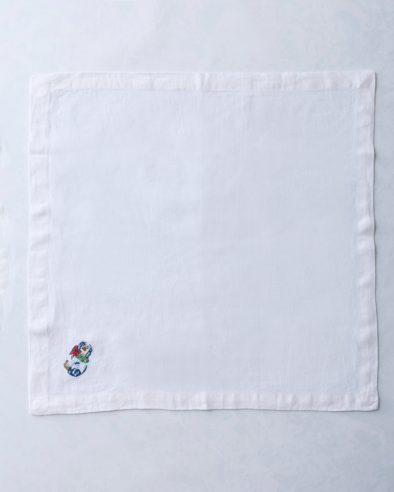 Single white dinner napkin with a small embroidered dog figurine near one corner