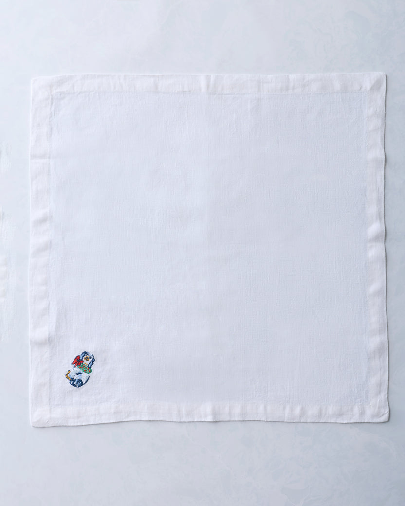 Single white dinner napkin with a small embroidered dog figurine near one corner