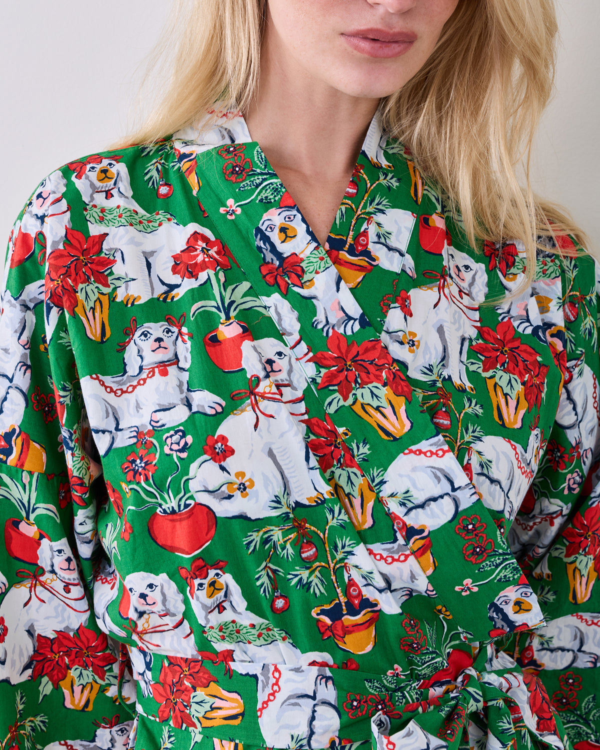 Close-up of the green robe's collar, overlapping front, matching belt, and festive dog-and-poinsettia print.