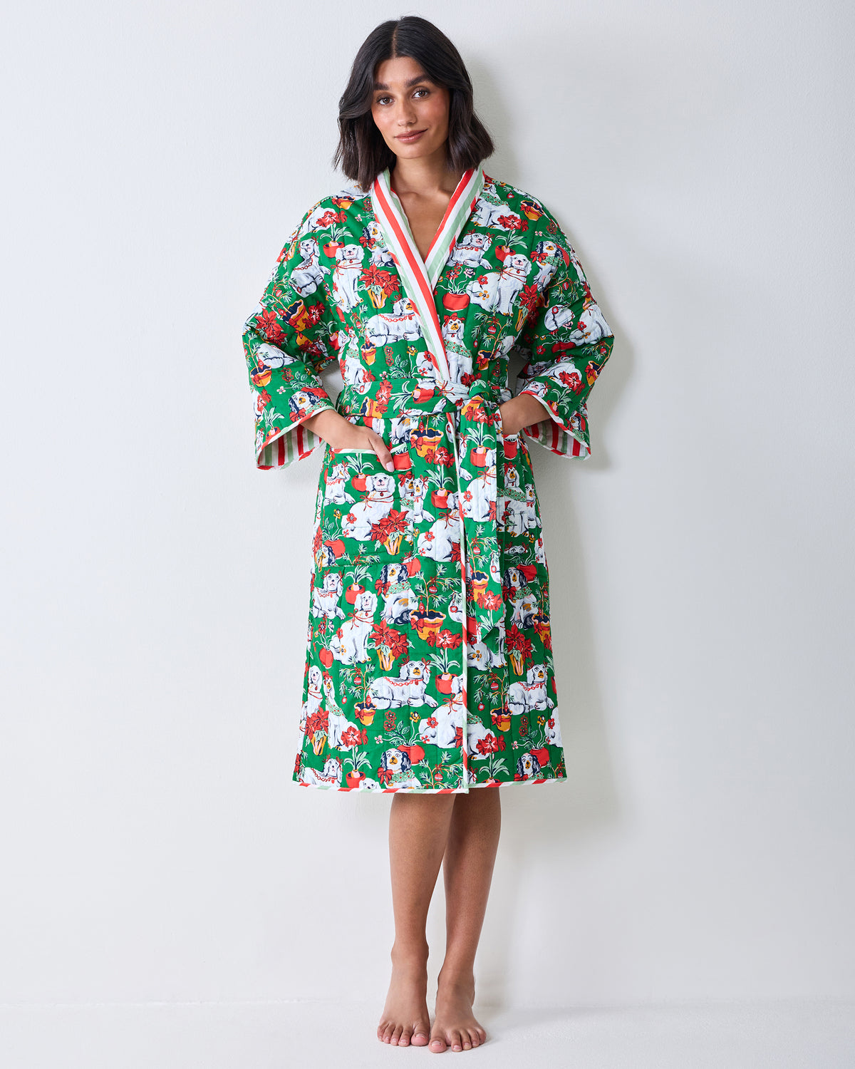 Full-length front view of a person wearing a green printed reversible quilted robe with a matching belt and pockets.