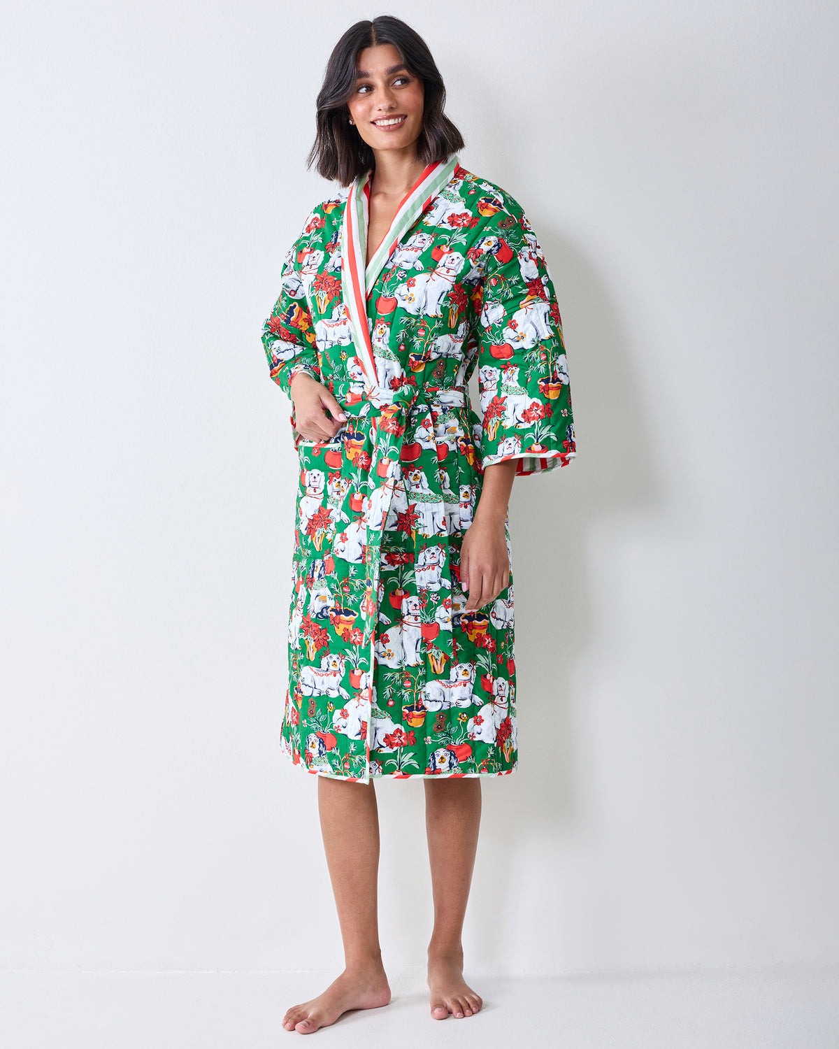 Three-quarter front view of a person wearing a green Christmas dog print robe with striped sleeve lining and a matching belt.