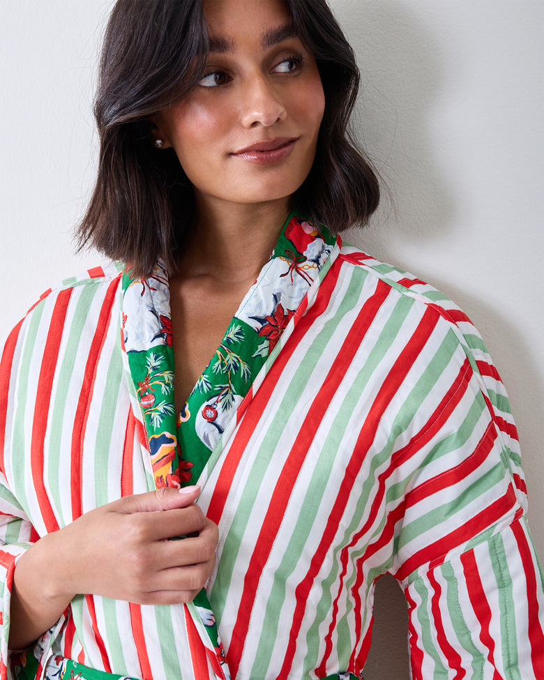Close front view of a reversible robe showing its red-and-green vertical striped side and patterned green trim.