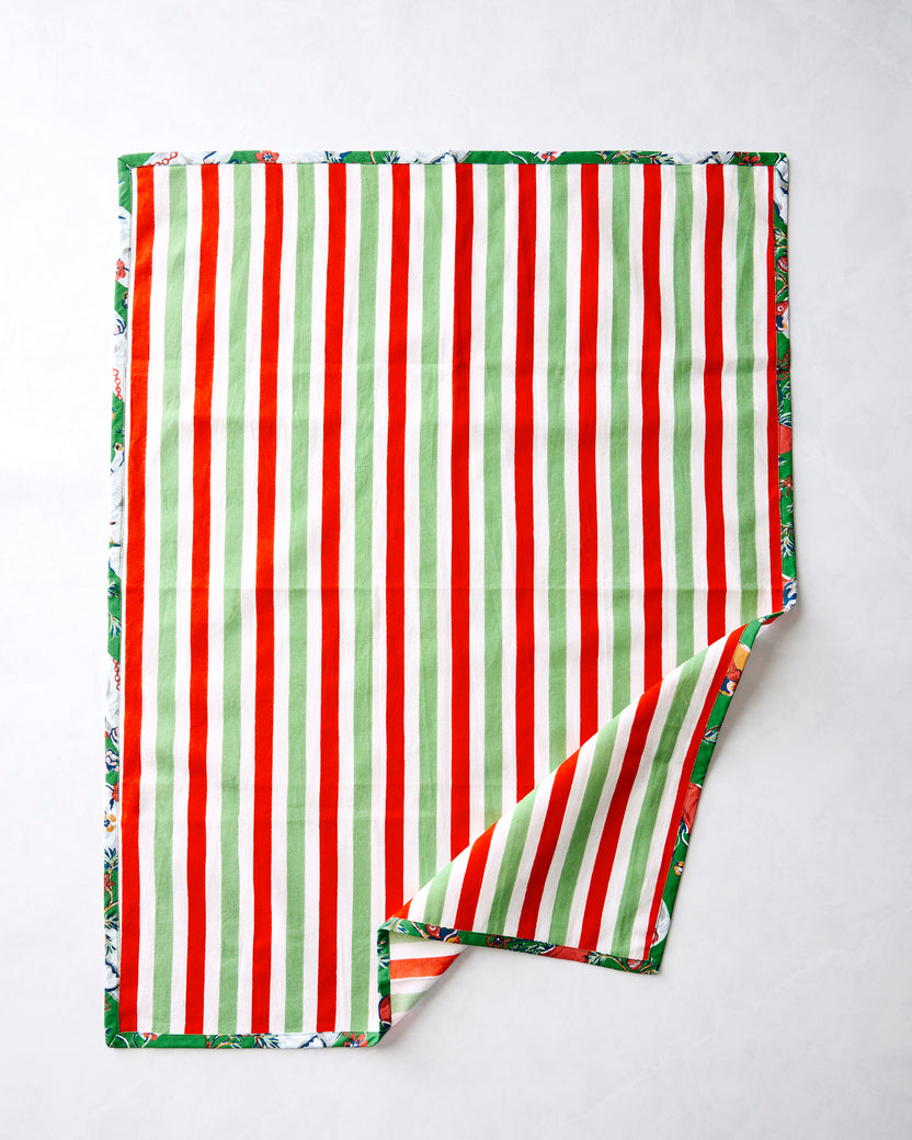 Reverse side of a Good Dog Christmas tea towel with vertical red, green, and white stripes and a patterned border.