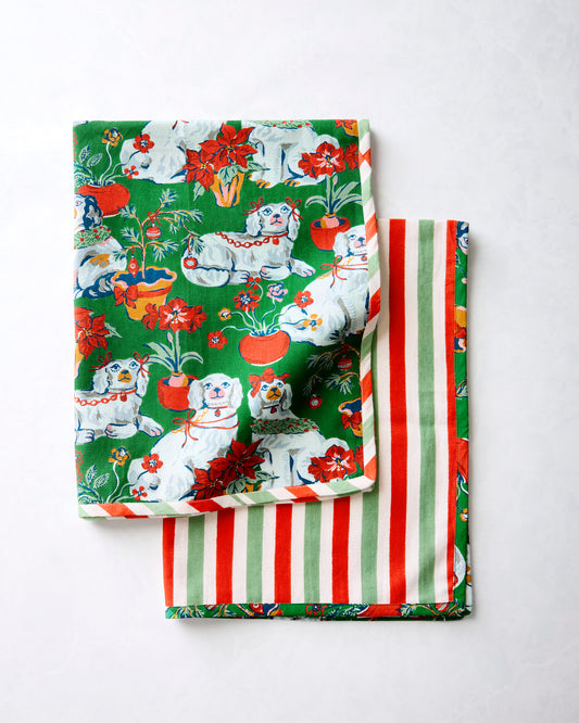 Two Good Dog Christmas tea towels layered together, showing the dog-and-flower print and the red, green, and white striped design.