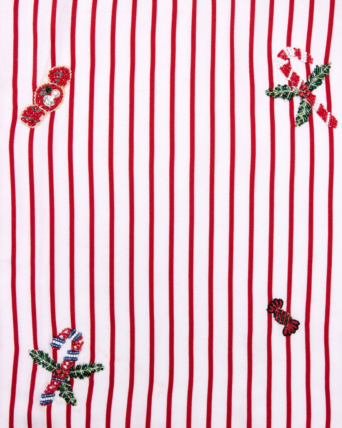 Close-up swatch of the Ellie set pattern with red vertical stripes and embroidered holiday motifs.
