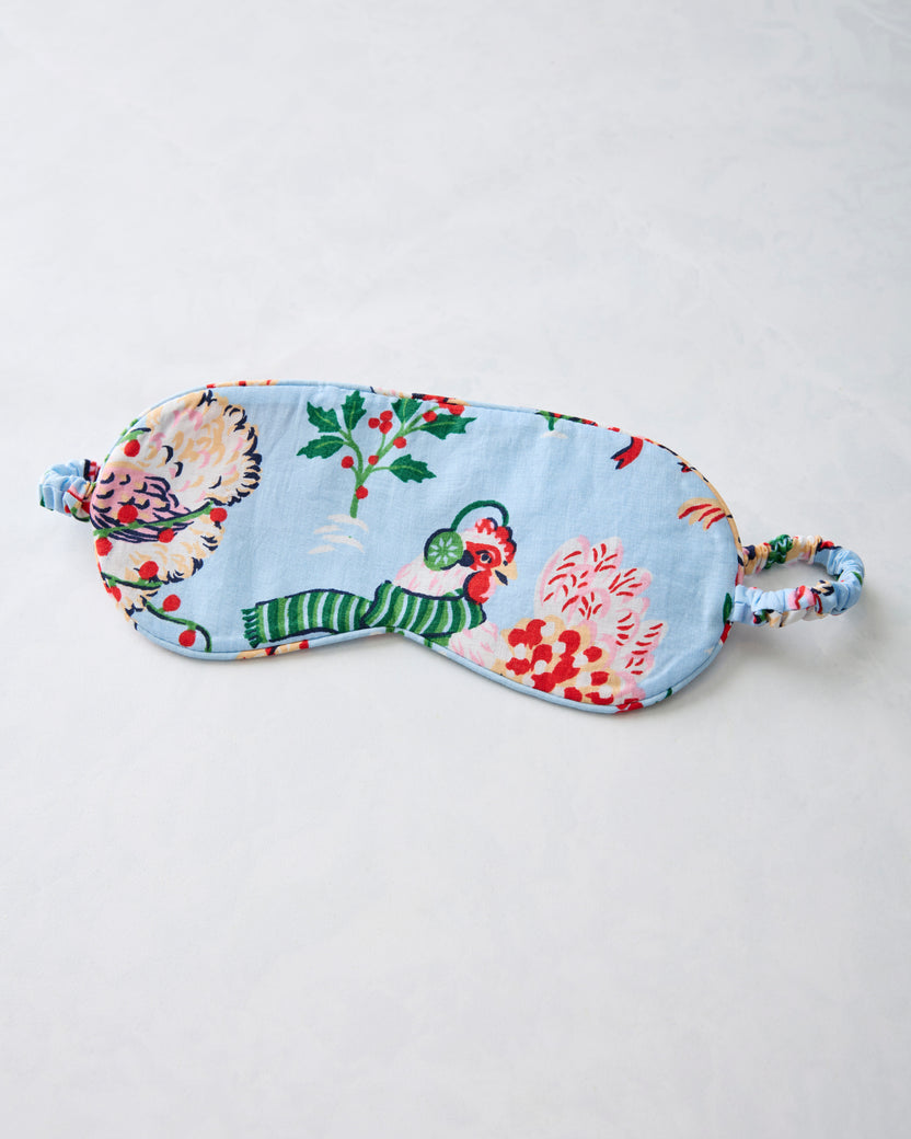 Pale blue eye mask with a floral and hen print and an adjustable elastic strap.