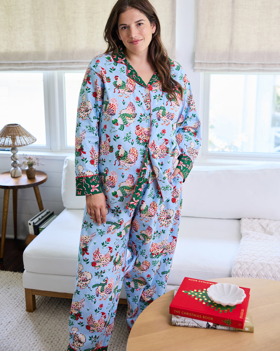 Person wearing the pale blue Holiday Hens long pajama set with a button-front top and full-length pants in a home setting.
