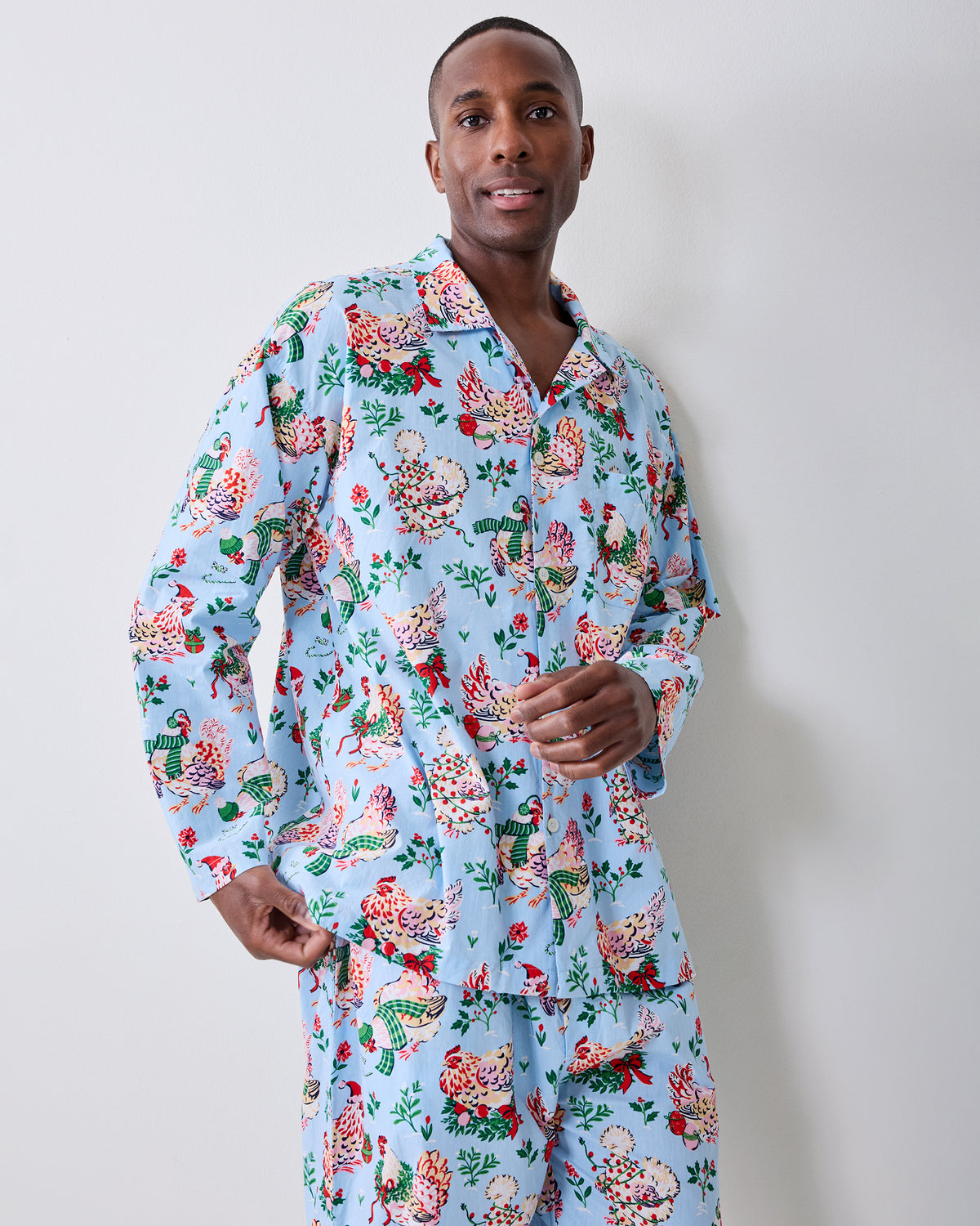 Person modeling a pale blue long-sleeve pajama shirt and pants with a holiday hen print.