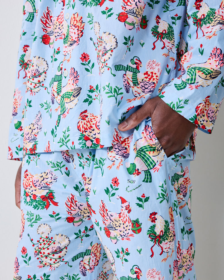 Close-up of the pale blue holiday hen pajama shirt and pants, showing the print, buttons, and pockets.