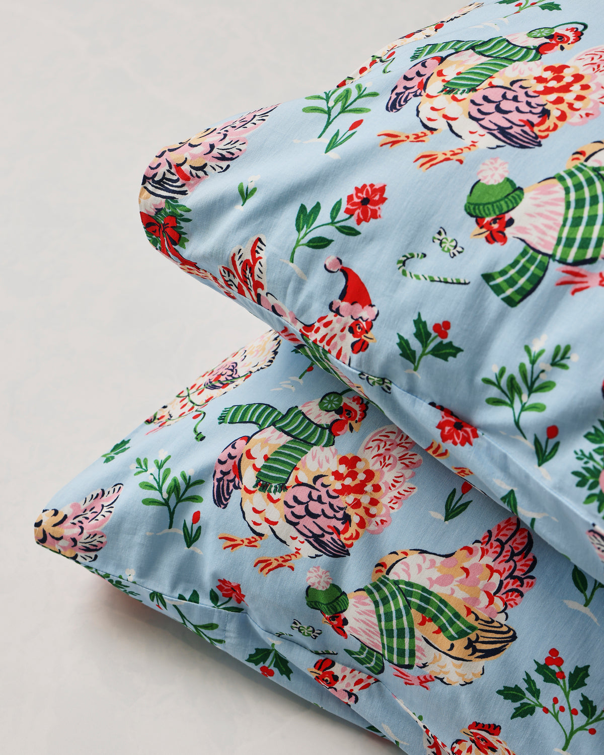 Close-up of two pale blue Holiday Hens pillowcases showing the printed hen design and finished edges.