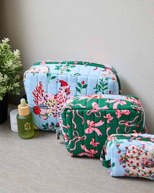Three quilted zip pouches in pale blue and green prints displayed on a tabletop.