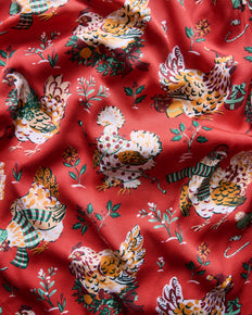 Close-up of the red Holiday Hens print featuring chickens, botanical sprigs, and decorative accents.
