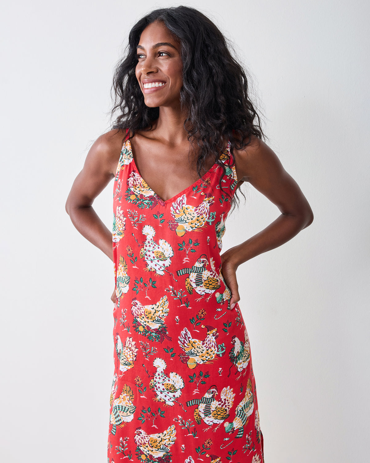 Front view of a model wearing the red Holiday Hens nightie with thin straps, a V-neck, and a printed hen pattern.