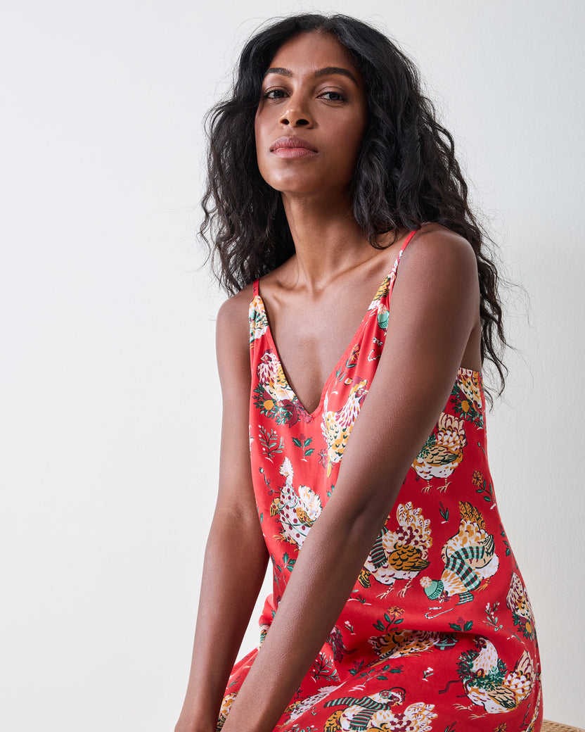 Close-up three-quarter view of a model wearing the red Holiday Hens nightie, showing the V-neck, straps, and patterned front and side.