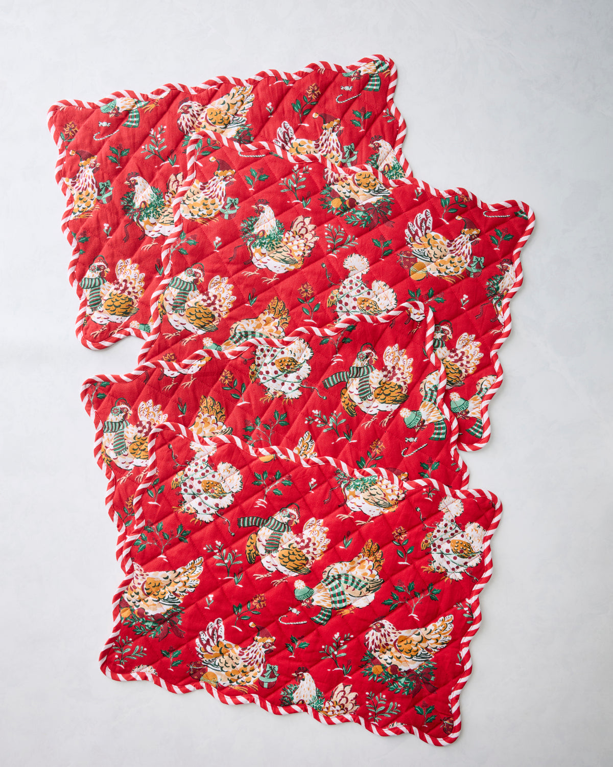 Four overlapping red scalloped placemats featuring an illustrated hen print.