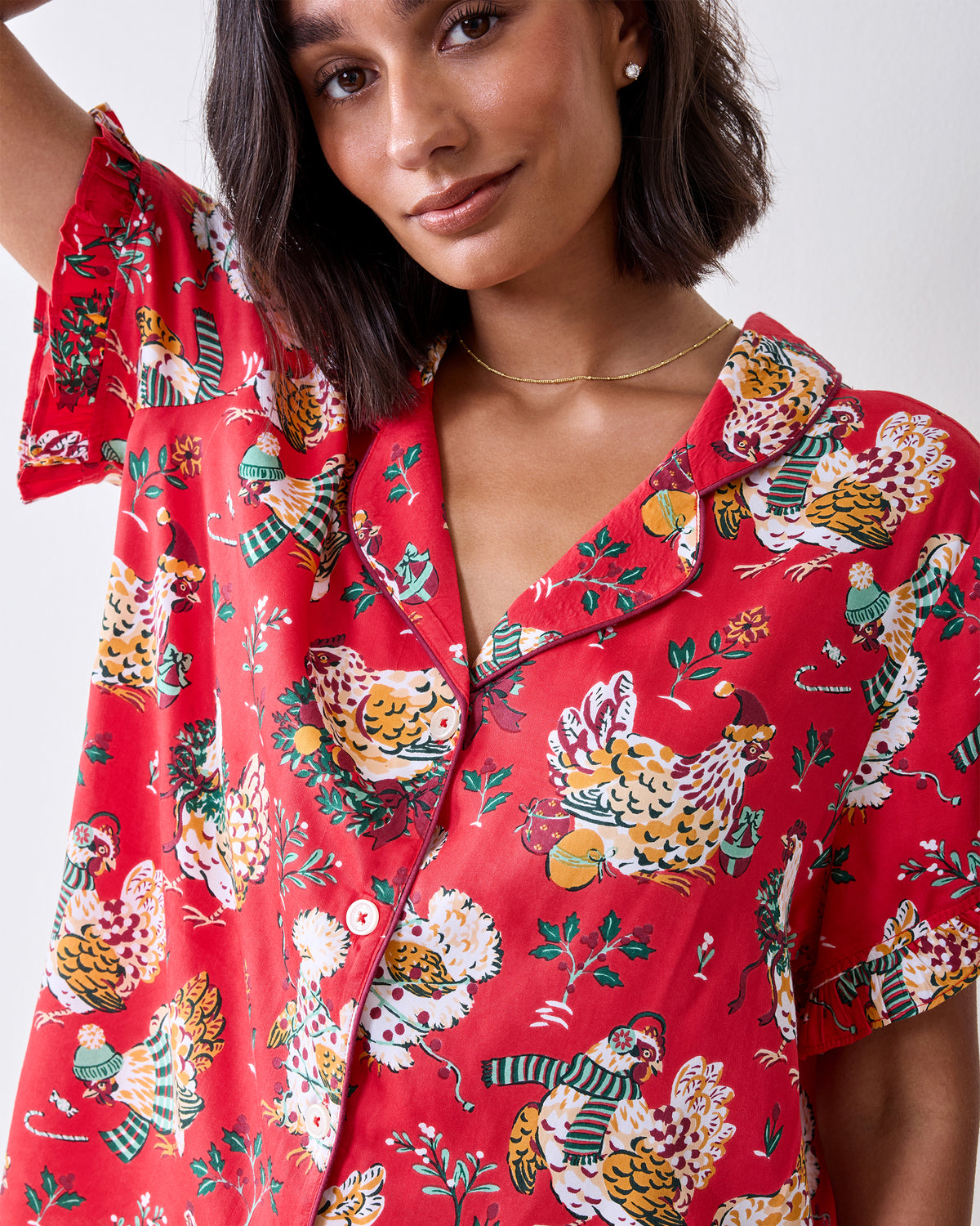 Close-up front view of the red Holiday Hens pajama top with contrasting piping, buttons, and chicken print.