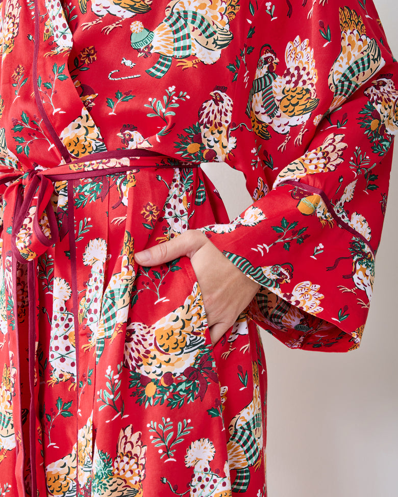 Close view of the red holiday hen-print robe showing its waist tie, sleeve trim, and side pocket.