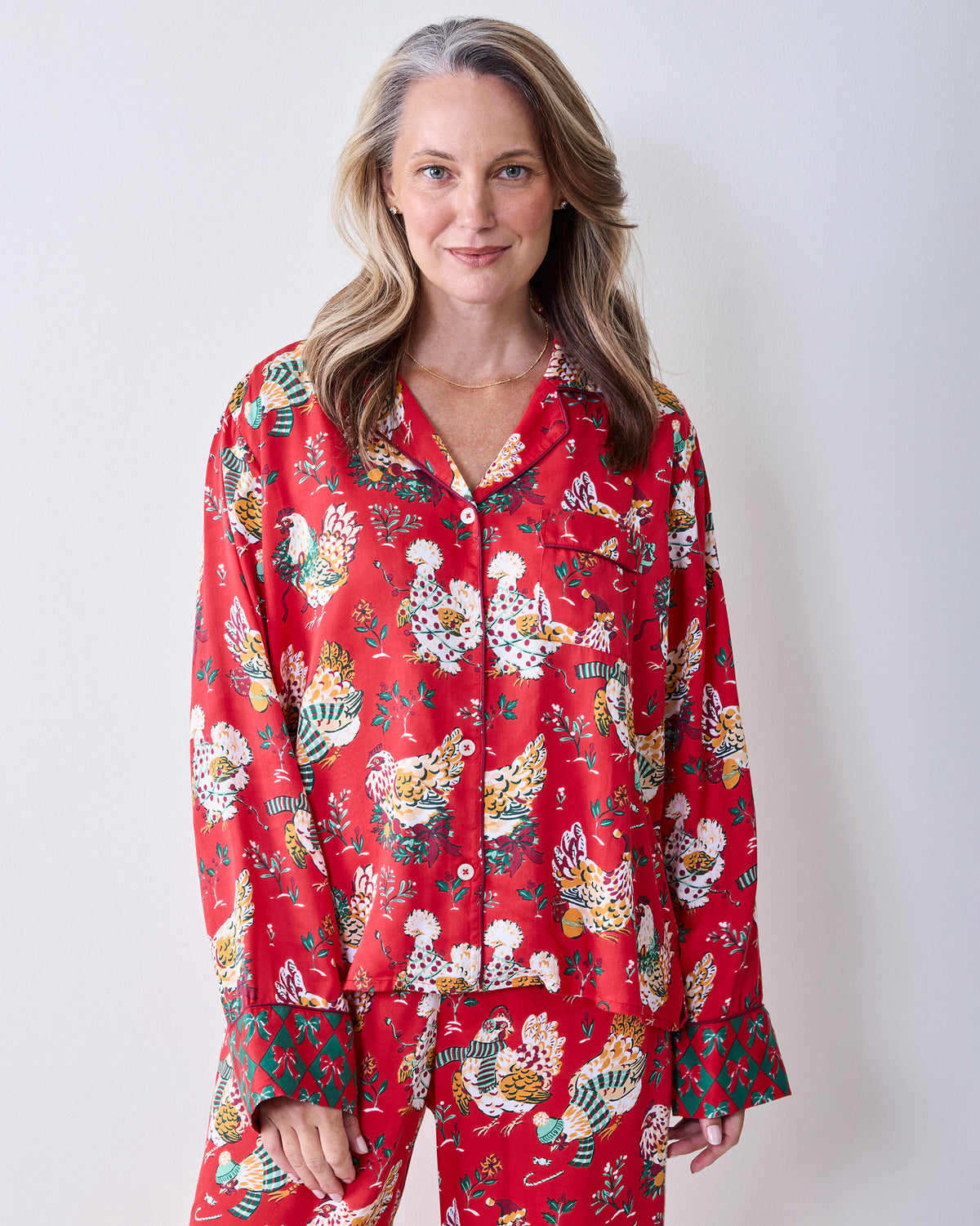 Front view of a person wearing the red Holiday Hens printed pajama set with a button-down top, chest pocket, and wide-leg pants.