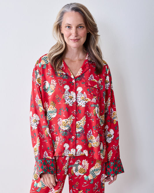 Front view of a person wearing the red Holiday Hens printed pajama set with a button-down top, chest pocket, and wide-leg pants.