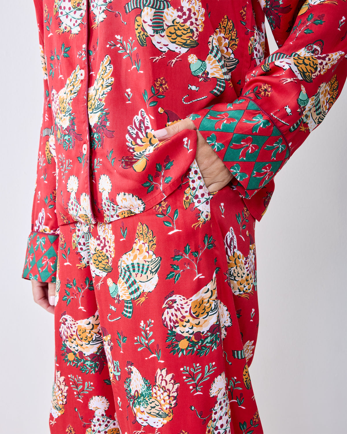 Close-up of the red Holiday Hens pajama set showing the printed pattern, side pocket, and contrasting cuff and hem details.