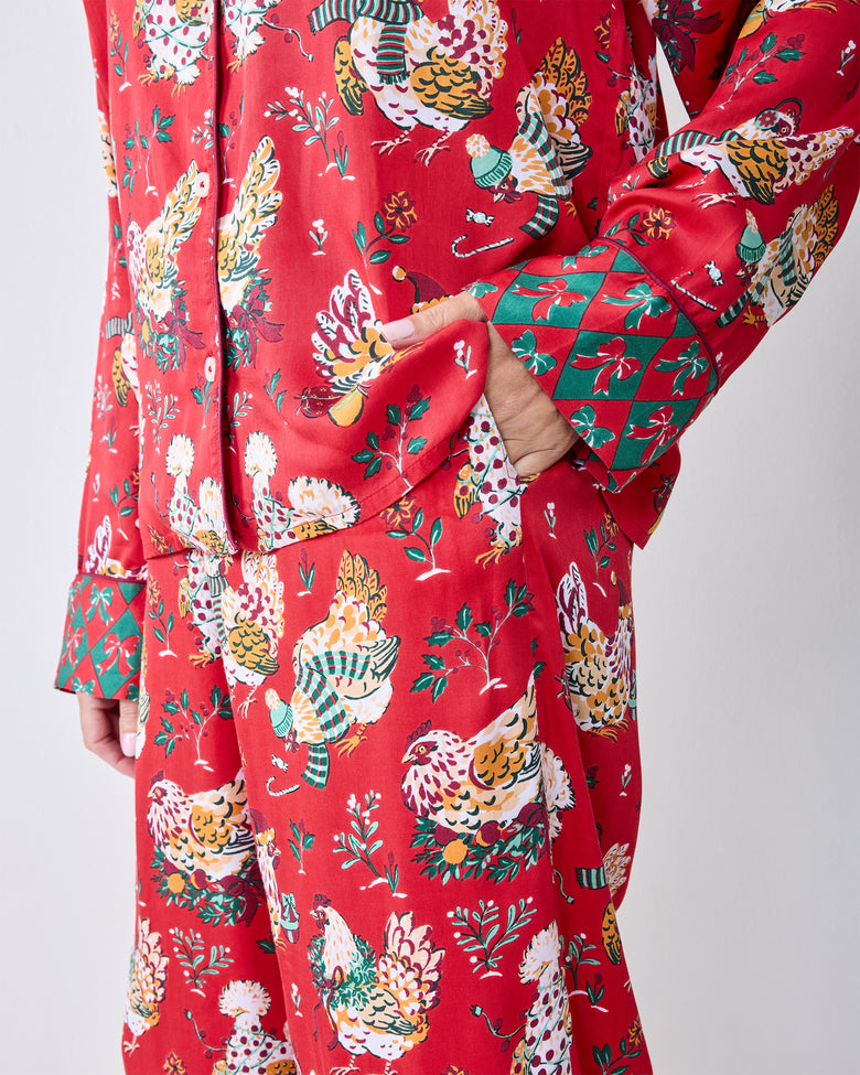 Close-up of the red Holiday Hens pajama set showing the printed pattern, side pocket, and contrasting cuff and hem details.