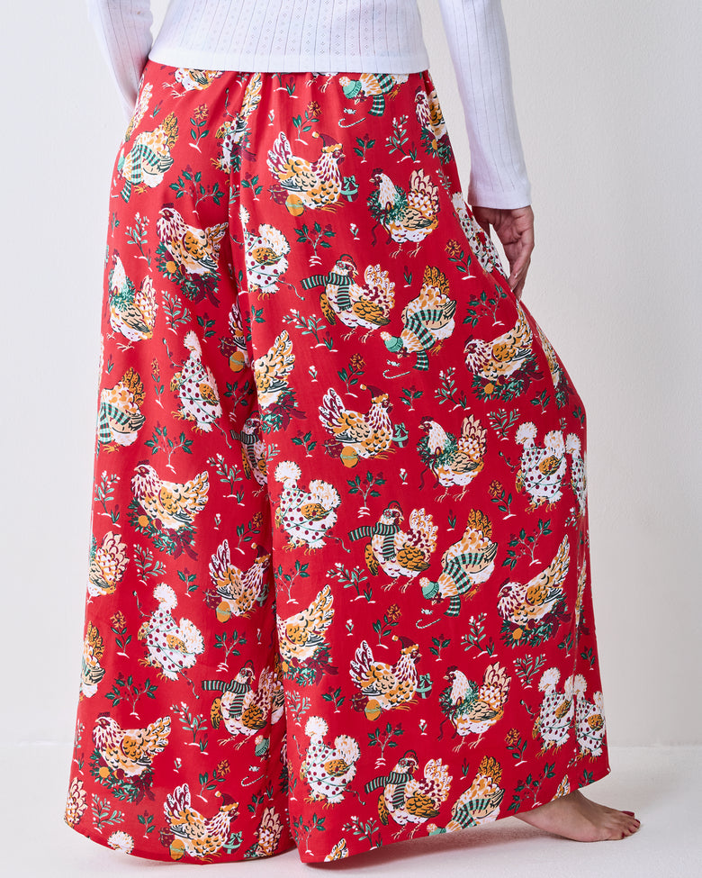 Back view of red Holiday Hens pants with a repeated colorful hen print and wide legs.