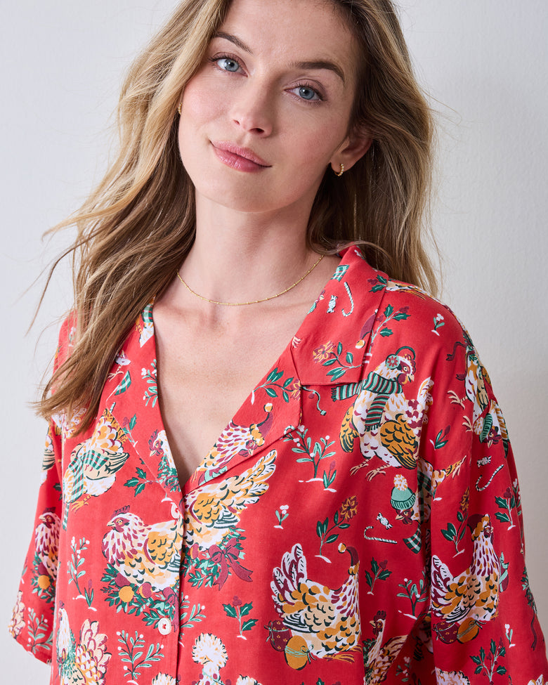 Close-up of the red Holiday Hens pajama top showing its V-neck, button front, short sleeves, and chicken print