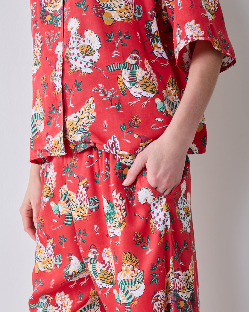 Close-up of the red Holiday Hens pajama set showing the printed short-sleeve top, wide-leg pants, and side pocket