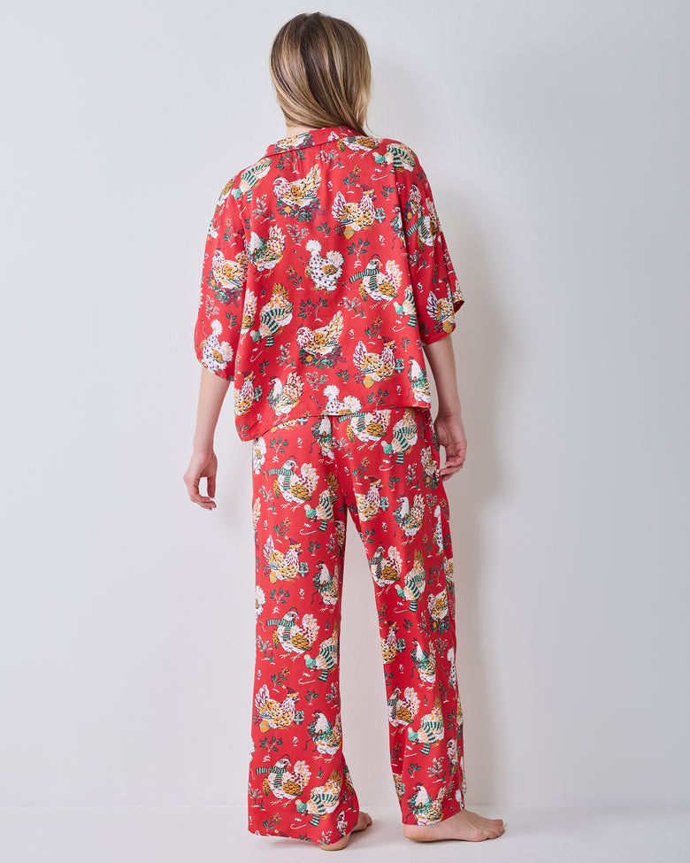 Back view of a person wearing the red Holiday Hens pajama set with a printed short-sleeve top and wide-leg pants.