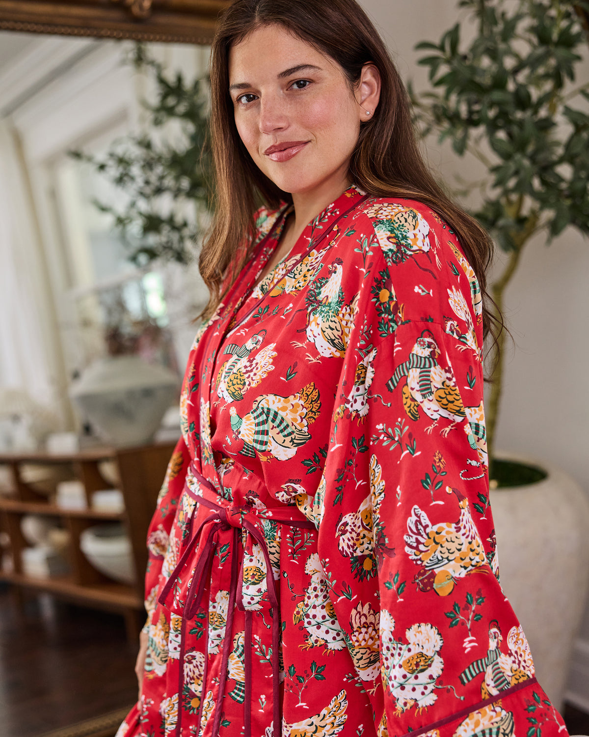Person wearing a red robe with a repeating holiday hen print, contrasting trim, and a waist tie.