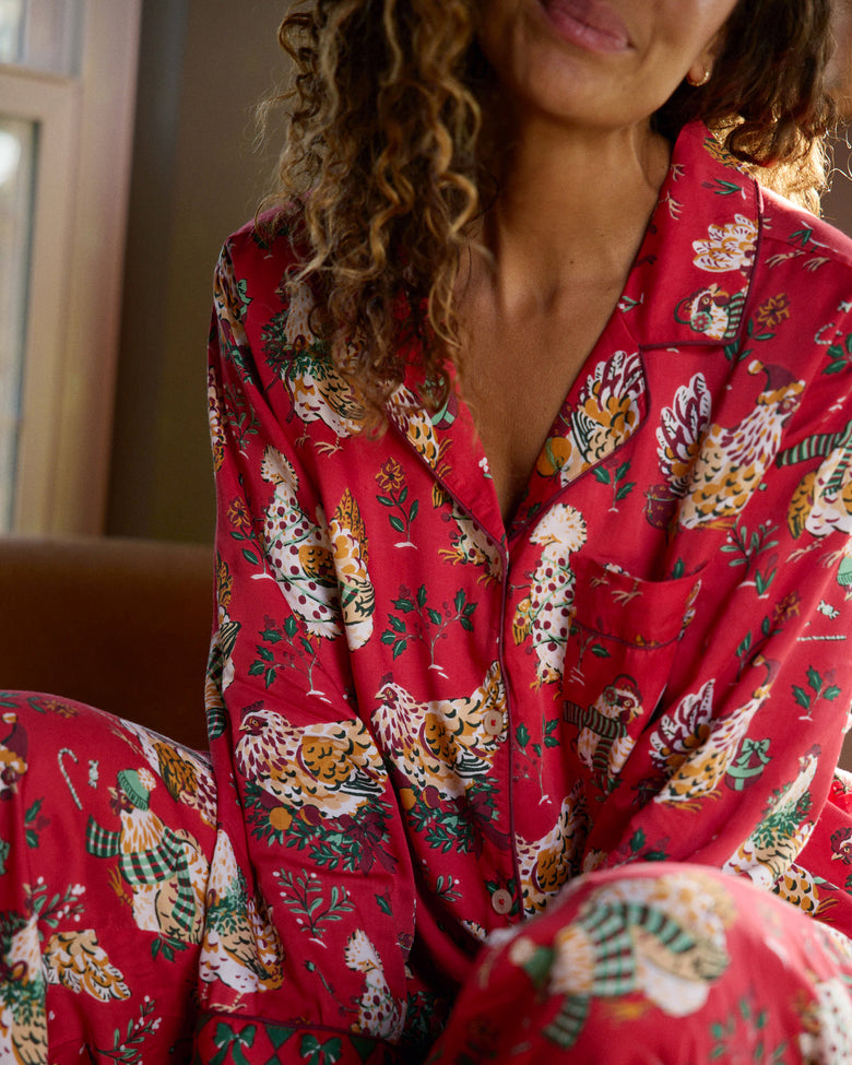 Close-up of the red Holiday Hens printed pajama top showing the notched collar, buttons, and chest pocket.