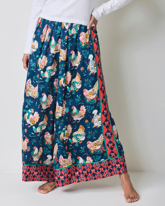 Holiday Hens satin pants shown full length with a dark blue chicken print, red patterned side stripe, and bordered hem.