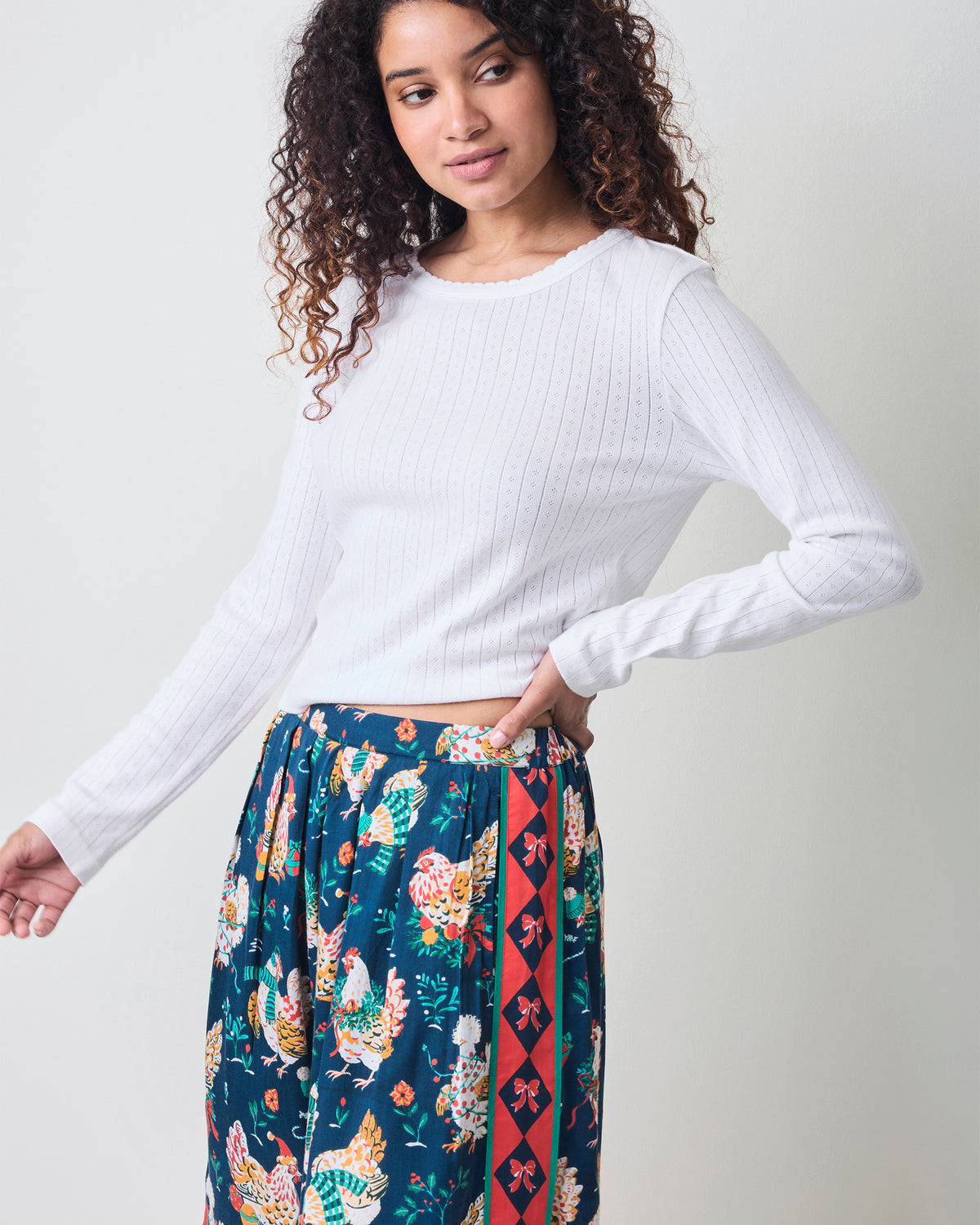 Front view of a person wearing the Holiday Hens satin pants with a dark blue chicken print and red patterned side stripe.