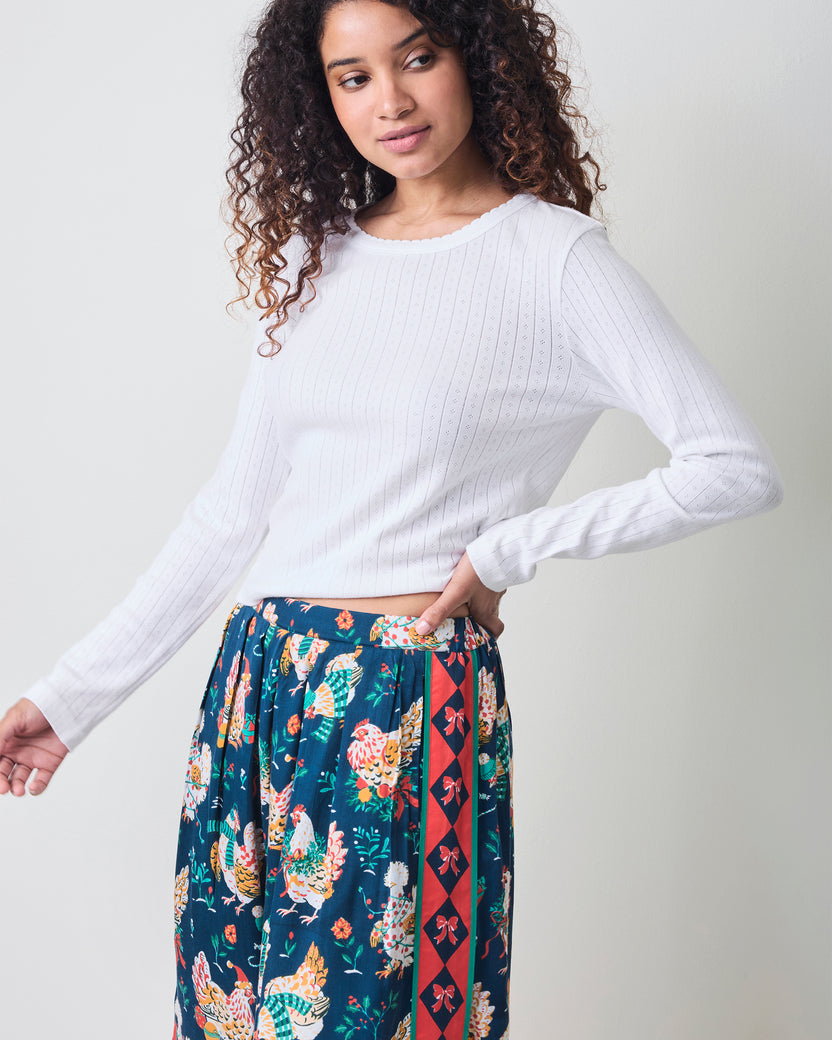 Front view of a person wearing the Holiday Hens satin pants with a dark blue chicken print and red patterned side stripe.