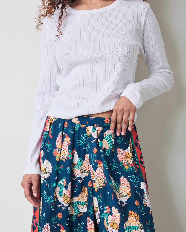 Close view of the Holiday Hens satin pants showing the elastic waistband, dark blue chicken print, and red patterned side stripe.