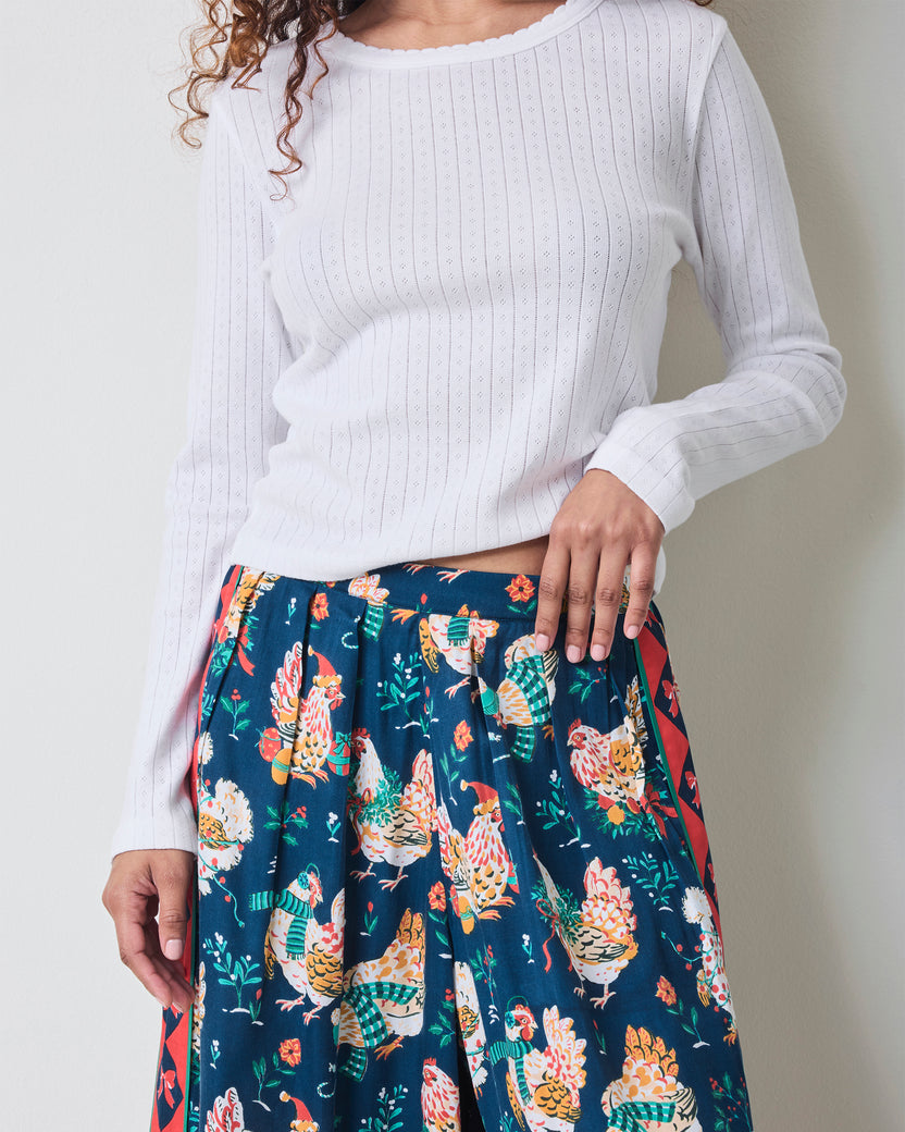Close view of the Holiday Hens satin pants showing the elastic waistband, dark blue chicken print, and red patterned side stripe.