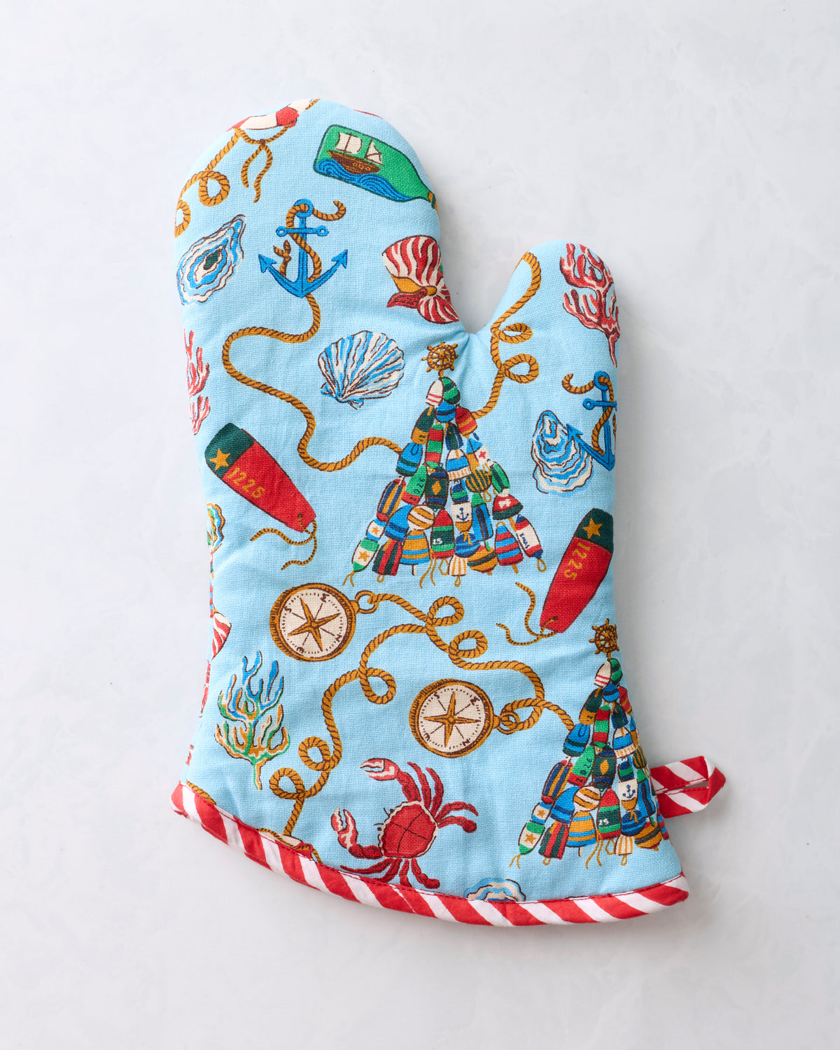Blue printed oven mitt with a red-and-white striped trim and nautical Christmas motifs.