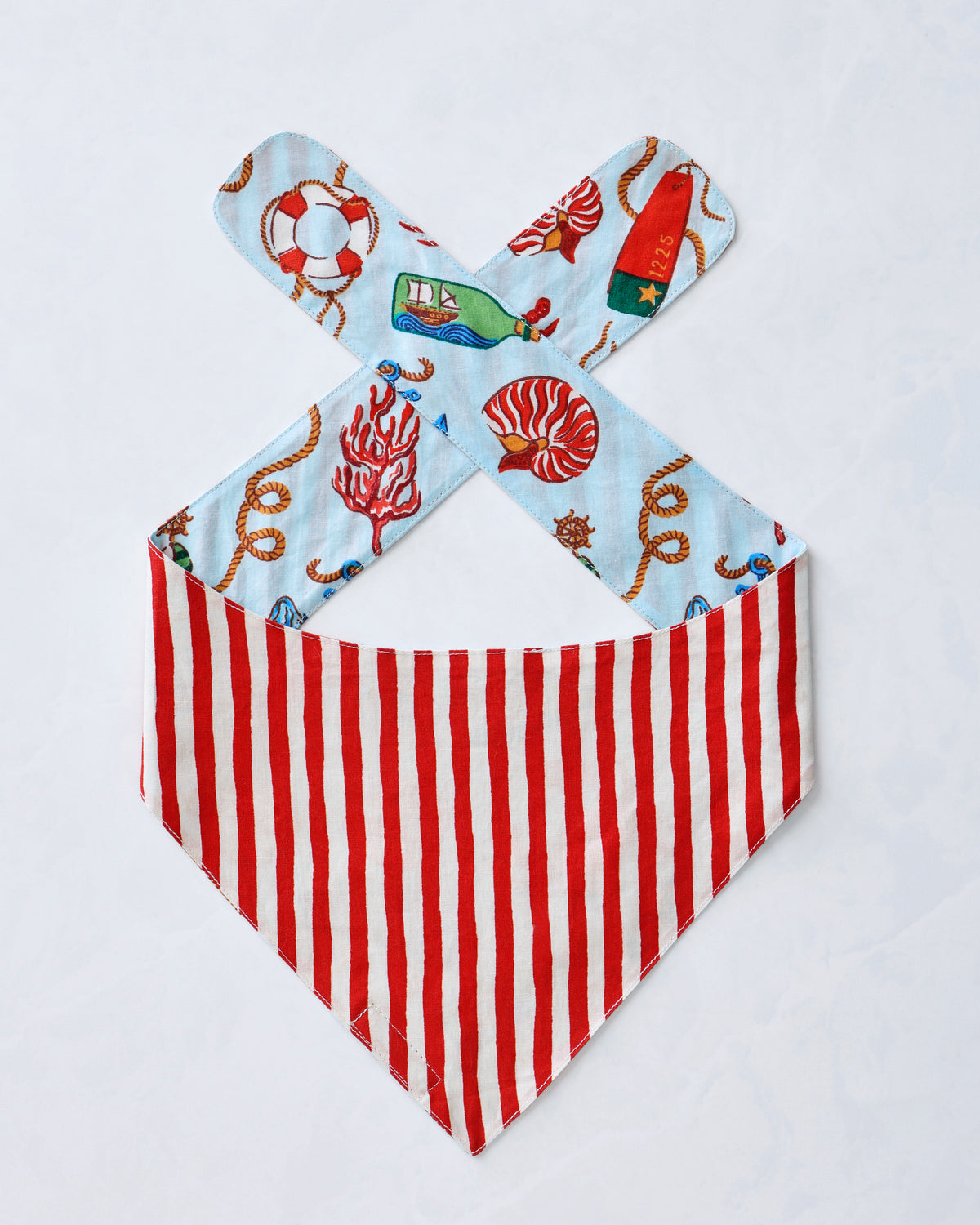 Blue nautical-print pet bandana with a red-and-white striped triangular panel and crossed ties.