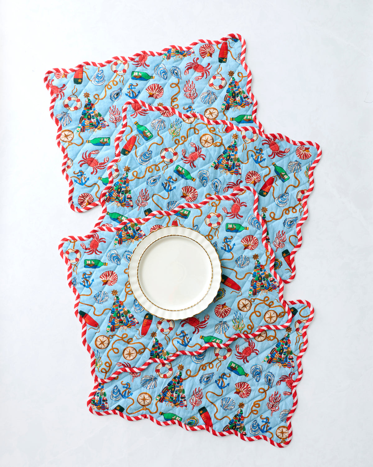 Four nautical-print placemats arranged with a plate on a white surface.