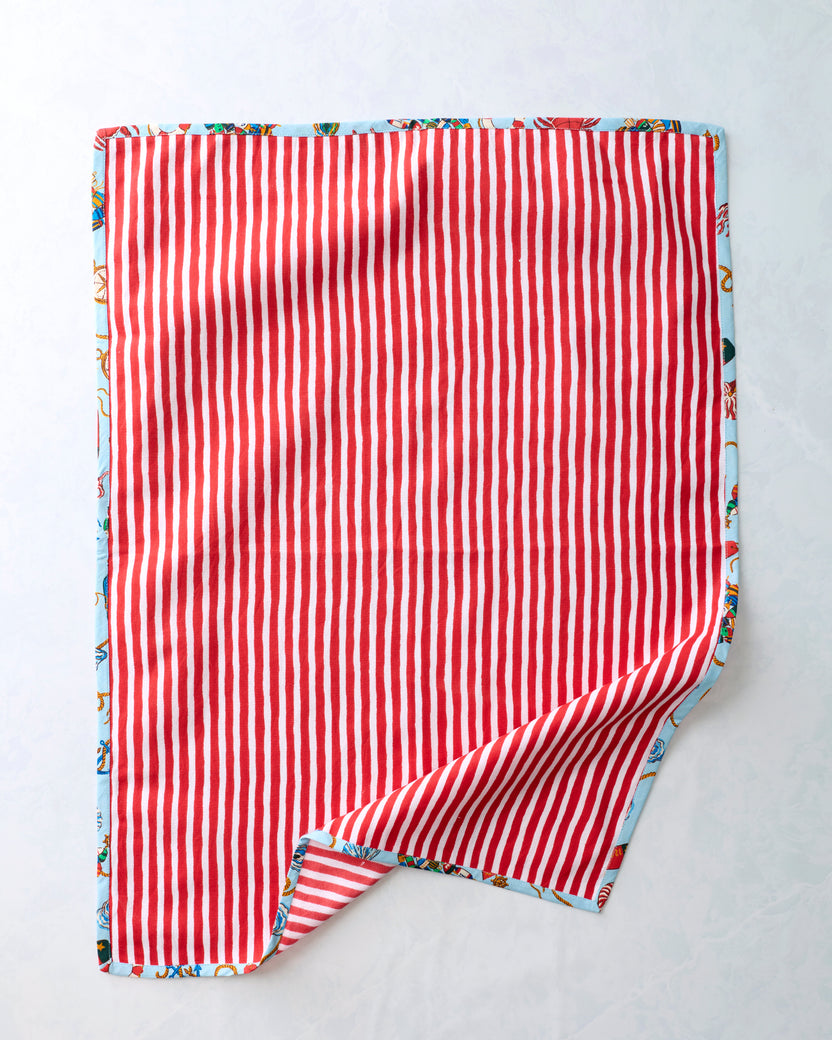 Reverse side of a tea towel with red-and-white vertical stripes; a folded corner reveals the blue printed side.