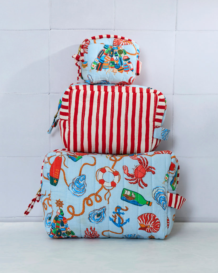 Three pouches stacked vertically, showing a pale blue nautical print and a red-and-white striped pouch.