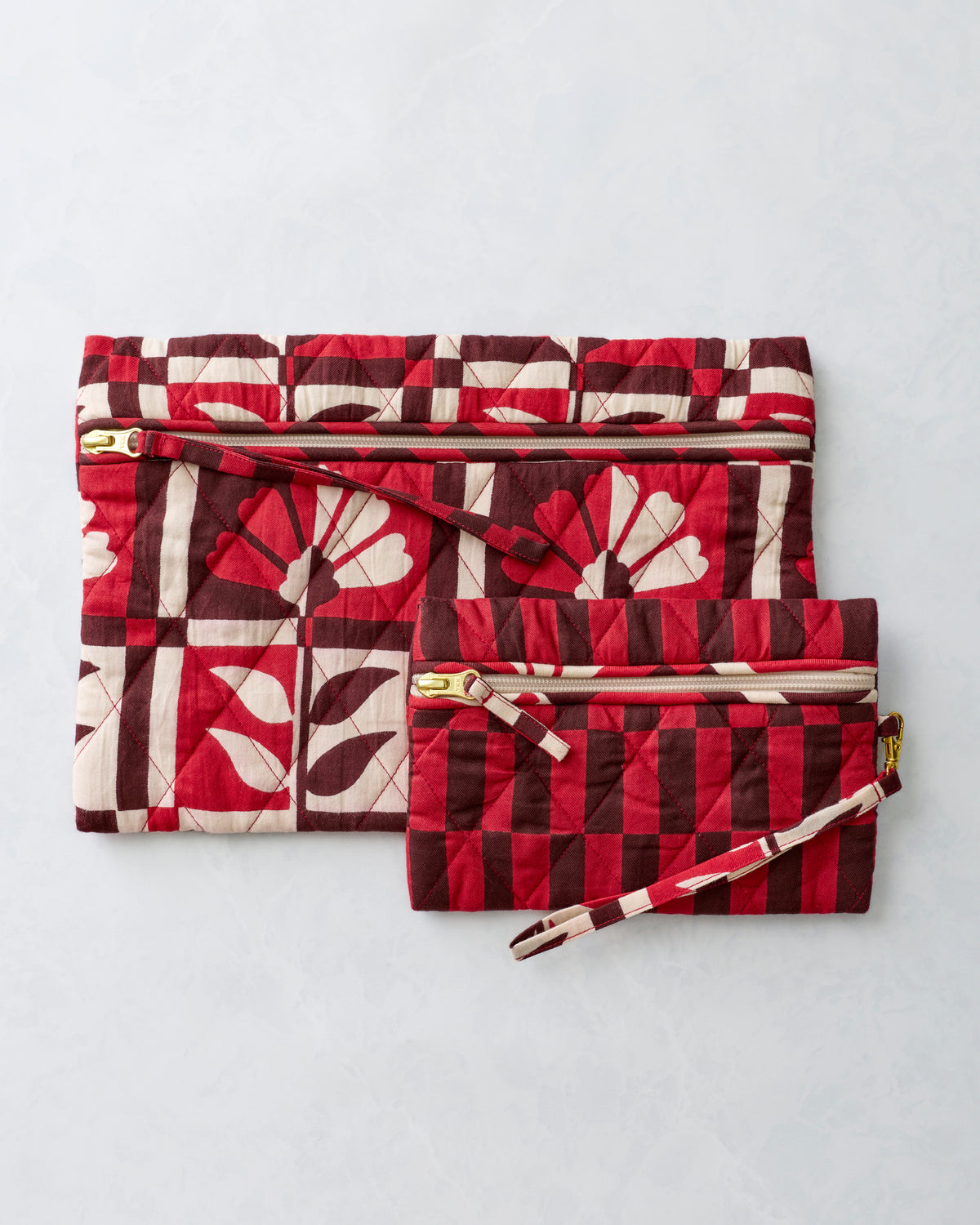 Two quilted zippered pouches in the Poppy print, shown overlapping with wrist straps visible.
