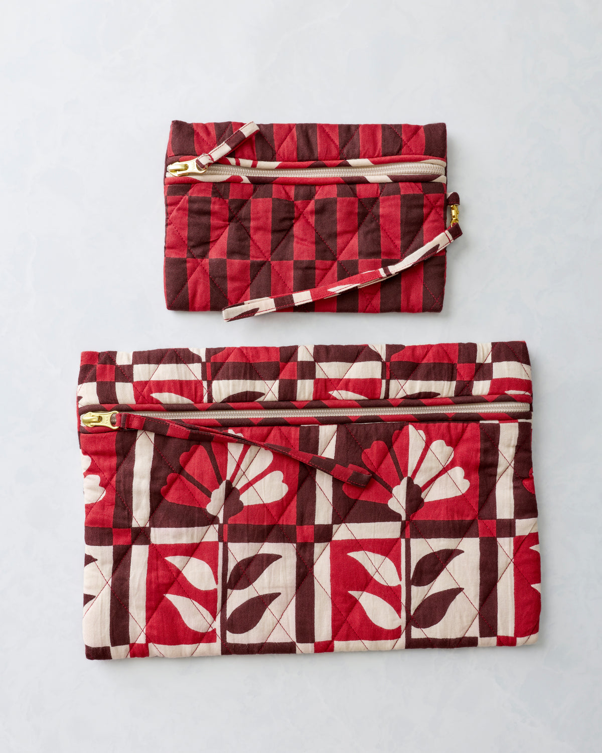 Two quilted zippered pouches in the Poppy print, arranged separately with the smaller pouch above the larger pouch.