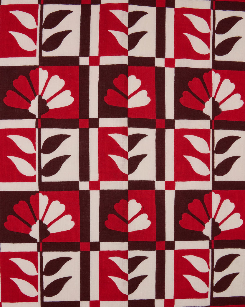 Hygge Greenhouse pattern swatch with stylized flowers and leaves in red, cream, and dark brown geometric blocks.