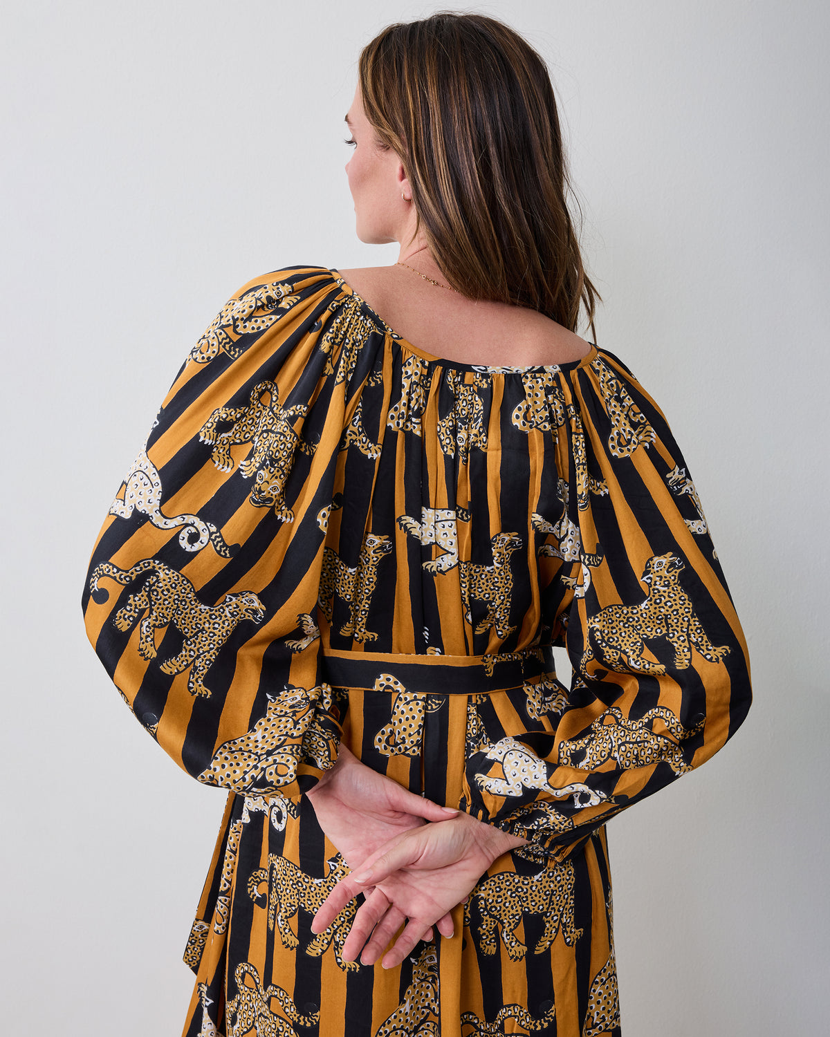 Back view of the Leopard Stripes Felicity dress showing the gathered neckline, long sleeves, waist tie, and printed fabric.
