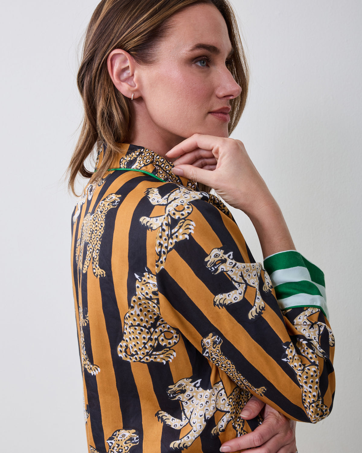 Close-up side view of the Soho pajama top showing leopard illustrations on butterscotch-and-black stripes and a green-and-white striped cuff.