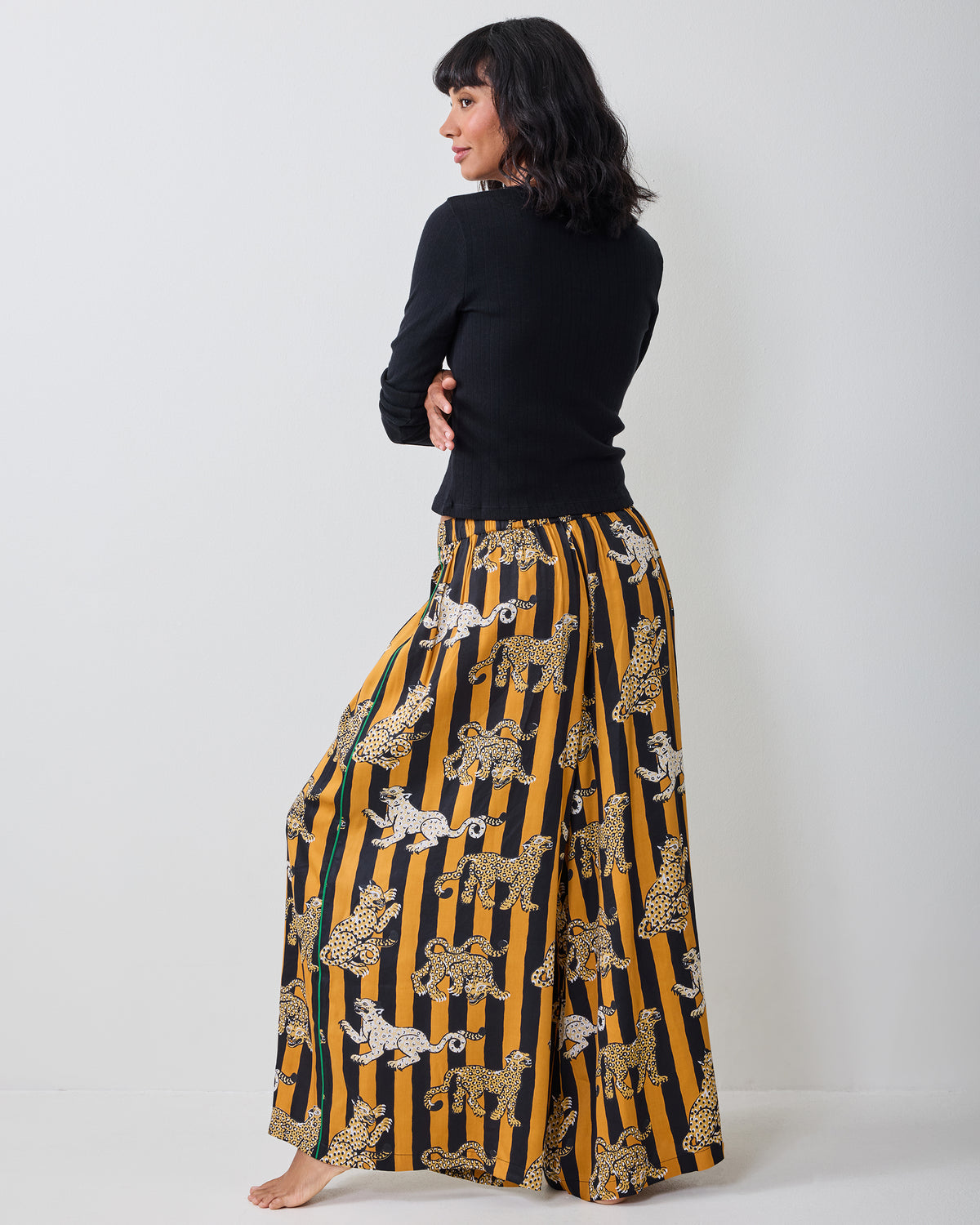 Back view of the Leopard Stripes Tribeca pants, showing the wide-leg silhouette and patterned butterscotch-and-black stripes.